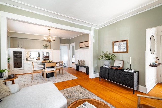 living room featuring crown molding, an inviting chandelier, and wood finished floors