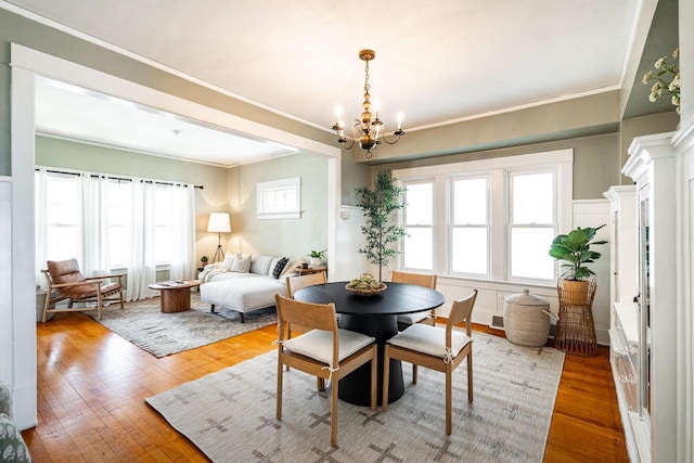dining space with crown molding, wood finished floors, a chandelier, and visible vents