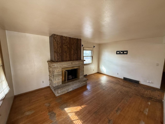 unfurnished living room featuring visible vents, a fireplace, and hardwood / wood-style flooring