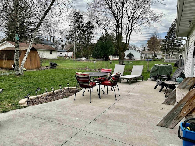 view of patio / terrace featuring a fenced backyard, a storage unit, outdoor dining space, and an outdoor structure