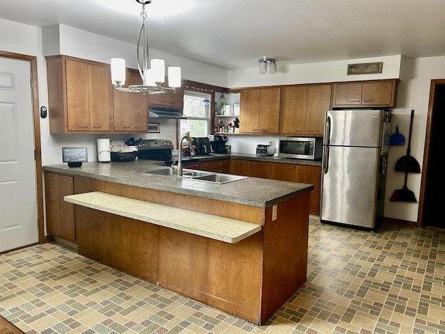 kitchen with exhaust hood, appliances with stainless steel finishes, brick patterned floor, a peninsula, and an inviting chandelier