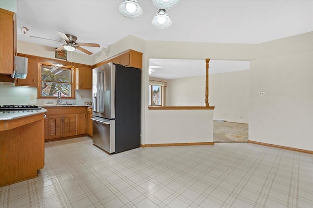 kitchen with ceiling fan, appliances with stainless steel finishes, brown cabinets, light countertops, and a sink