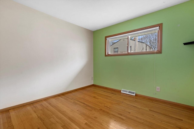 spare room with baseboards, light wood finished floors, and visible vents