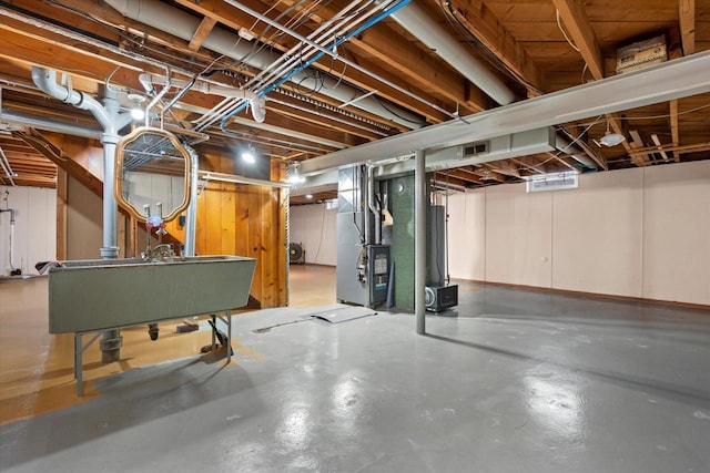 unfinished below grade area featuring visible vents, heating unit, and water heater