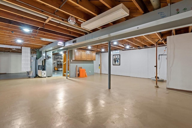 below grade area with heating unit, water heater, and visible vents