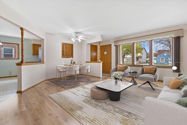 living area with a ceiling fan, baseboards, and light wood-style floors