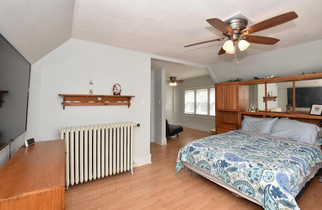 bedroom featuring a ceiling fan, lofted ceiling, wood finished floors, and radiator