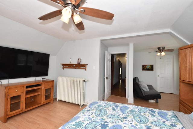 bedroom featuring ceiling fan, lofted ceiling, radiator, and light wood-type flooring