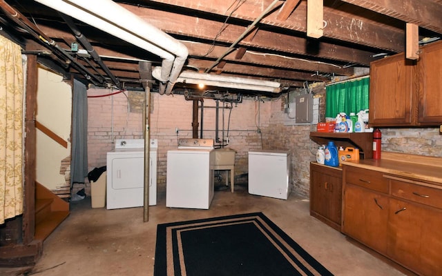 unfinished below grade area with separate washer and dryer, a sink, electric panel, and fridge