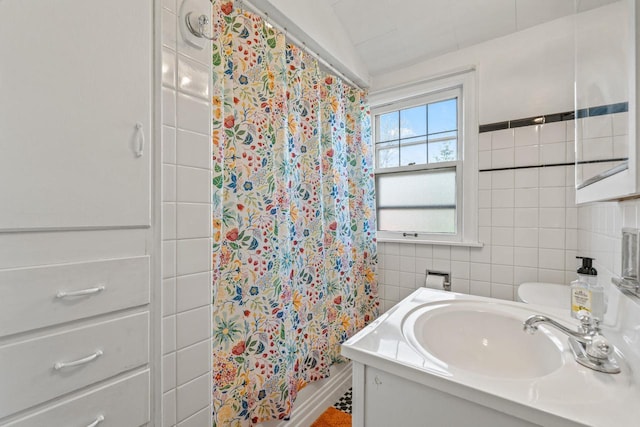 full bath with tile walls, a shower with shower curtain, and vanity
