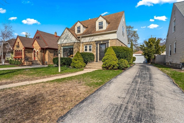view of front of house featuring brick siding, an outbuilding, a front lawn, and a garage
