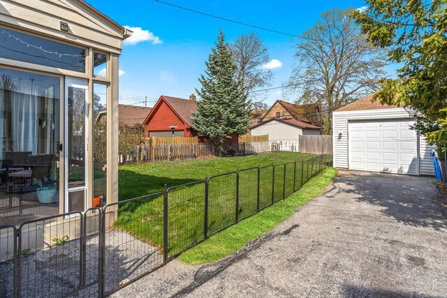 view of yard featuring fence, a detached garage, an outdoor structure, and driveway