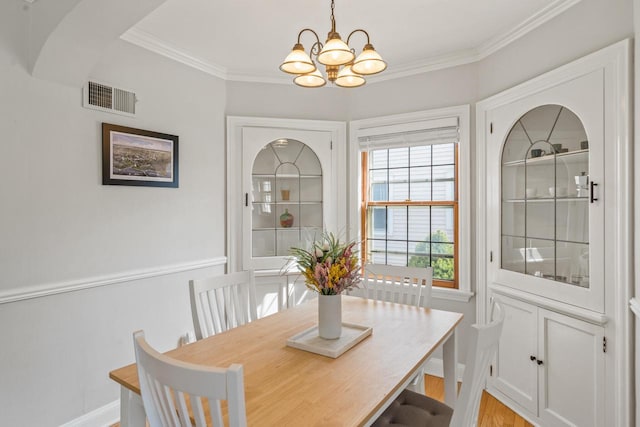 dining space with visible vents, baseboards, an inviting chandelier, ornamental molding, and light wood-style flooring