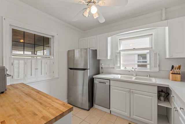 kitchen featuring ceiling fan, white cabinets, a sink, appliances with stainless steel finishes, and light tile patterned floors