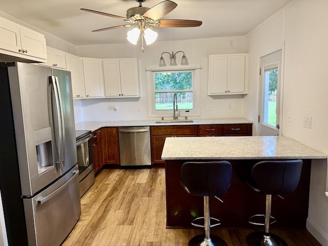 2334 16th Ave, Monroe, WI 53566 - kitchen featuring stainless steel appliances, a sink, a kitchen bar, light wood-type flooring, and a peninsula