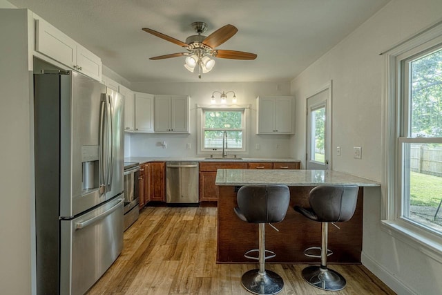 2334 16th Ave, Monroe, WI 53566 - kitchen with stainless steel appliances, a sink, light wood-style floors, light stone countertops, and a breakfast bar