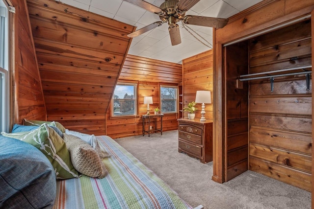 bedroom featuring wooden walls, ceiling fan, and carpet