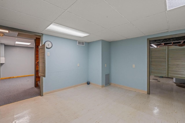 finished below grade area featuring baseboards, a drop ceiling, and visible vents