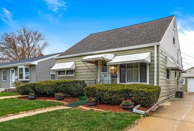 view of front of house with a shingled roof and a front yard