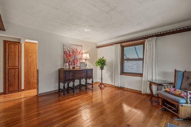 living area featuring baseboards, a textured ceiling, and wood finished floors