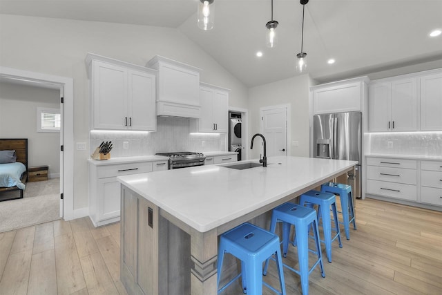 1205 Thistle Dew Ln, Waunakee, WI 53597 - kitchen with a sink, stainless steel appliances, stacked washer / dryer, vaulted ceiling, and a kitchen bar