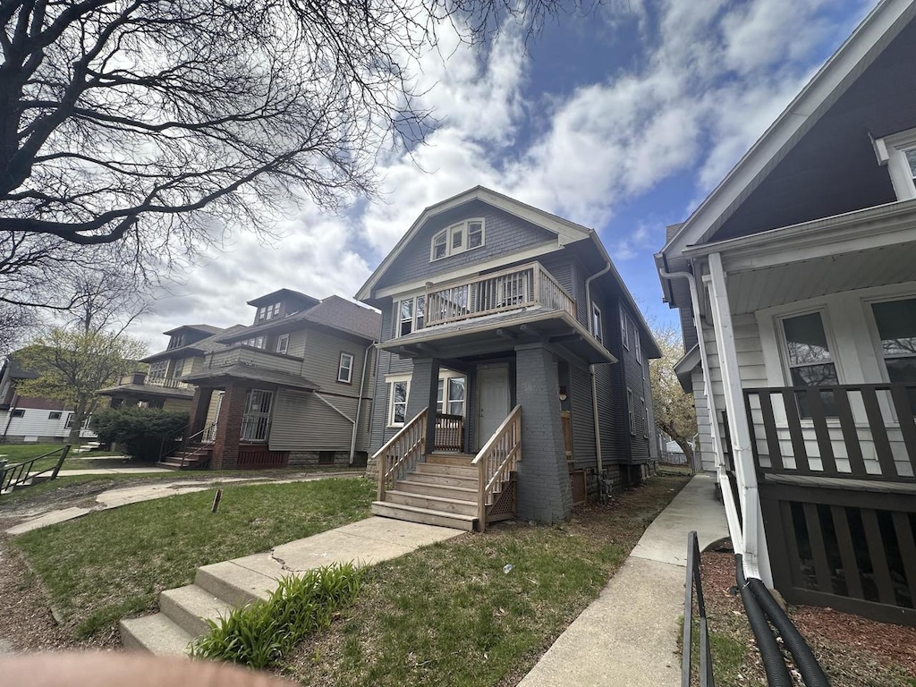 view of front of house featuring brick siding, a balcony, and a front yard