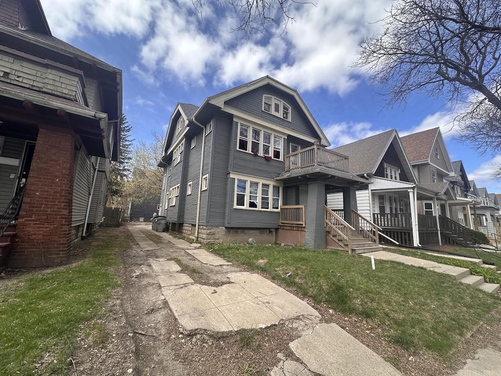 exterior space featuring a front yard, a balcony, and driveway