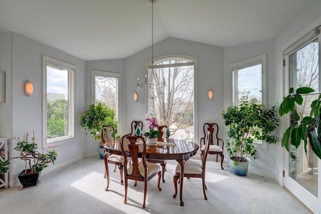 carpeted dining space featuring baseboards, vaulted ceiling, and plenty of natural light
