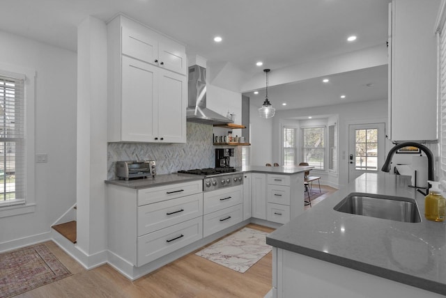 397 W Geneva St, Williams Bay, WI 53191 - kitchen featuring a sink, wall chimney exhaust hood, a peninsula, and light wood-style flooring