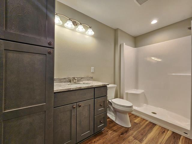 1093 W Queens Way, Nekoosa, WI 54457 - bathroom with vanity, toilet, wood finished floors, a shower, and visible vents