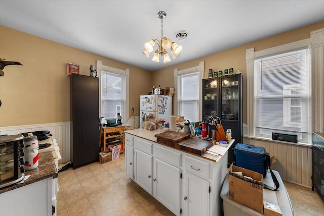 1932 N Warren Ave Unit 1934, Milwaukee, WI 53202 - kitchen featuring white cabinets, a notable chandelier, wainscoting, freestanding refrigerator, and pendant lighting
