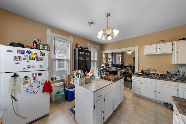 1932 N Warren Ave Unit 1934, Milwaukee, WI 53202 - kitchen with visible vents, freestanding refrigerator, white cabinets, a chandelier, and a sink