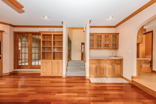 kitchen with visible vents, arched walkways, a sink, light wood-style floors, and ornamental molding