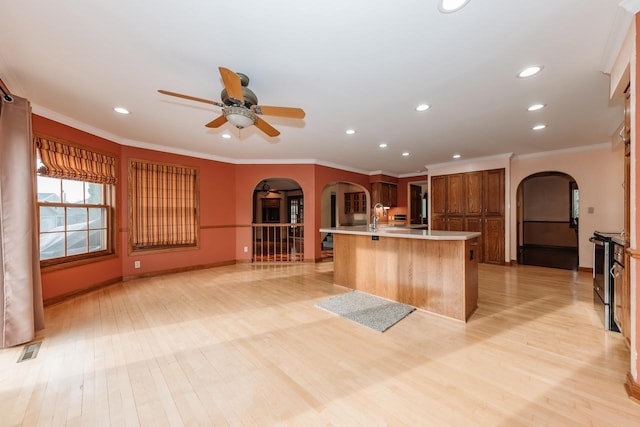 kitchen with visible vents, arched walkways, brown cabinetry, and light countertops