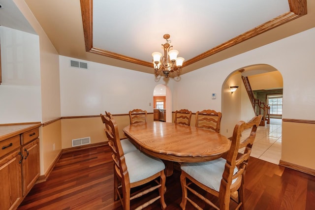 dining space featuring visible vents, arched walkways, a chandelier, and a tray ceiling