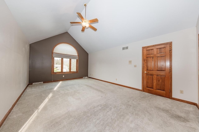 spare room with visible vents, baseboards, light colored carpet, a ceiling fan, and vaulted ceiling