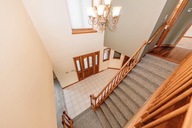 stairway featuring tile patterned floors, a high ceiling, carpet flooring, and a chandelier