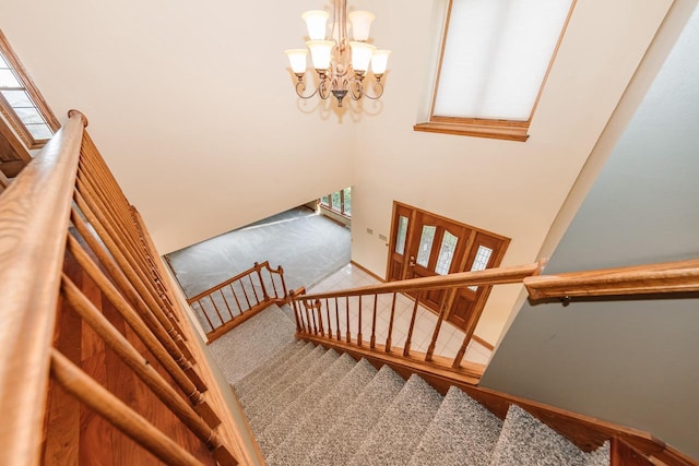 stairs featuring a high ceiling, a notable chandelier, baseboards, and carpet