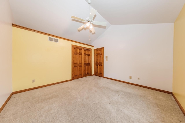empty room with ceiling fan, light colored carpet, visible vents, baseboards, and vaulted ceiling