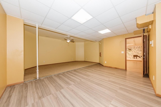empty room with a ceiling fan, baseboards, a paneled ceiling, and light wood finished floors