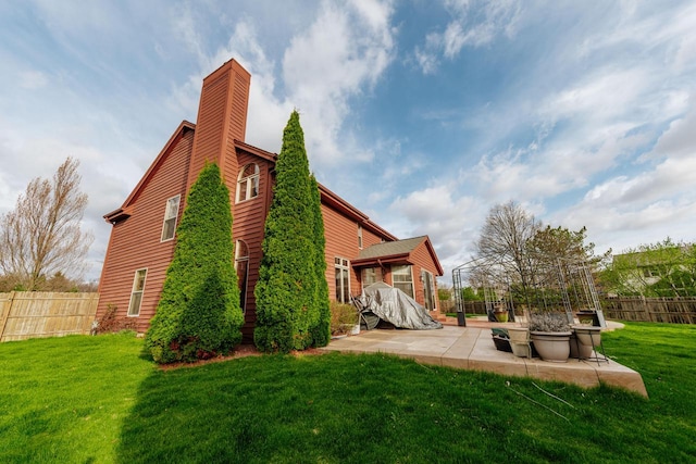 back of property featuring a patio, fence, a yard, and a chimney