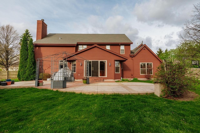rear view of property featuring a yard, a chimney, and a patio area
