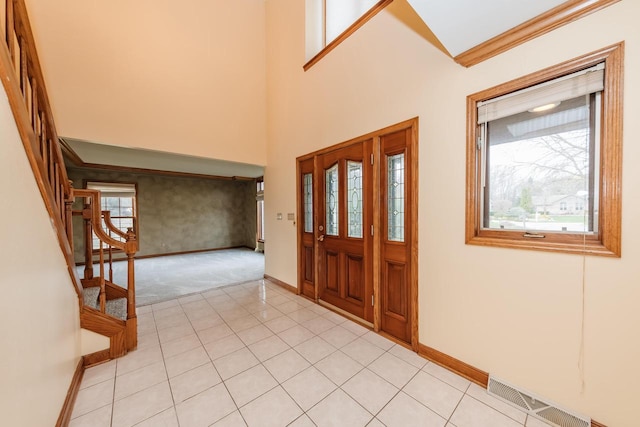 entrance foyer with visible vents, light colored carpet, baseboards, ornamental molding, and stairs