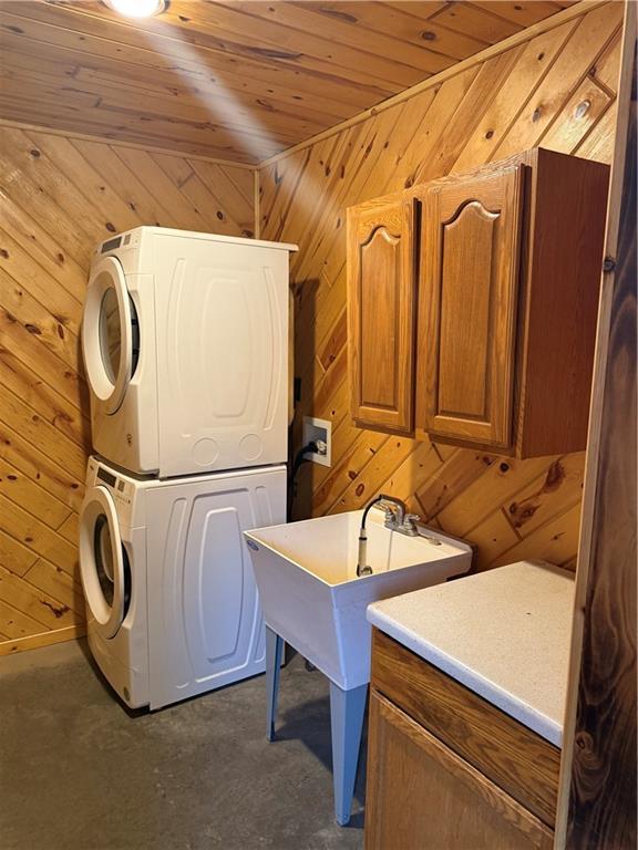 8523 Lakeside Rd, Trego, WI 54888 - laundry room featuring stacked washer and clothes dryer, cabinet space, wood walls, and wooden ceiling