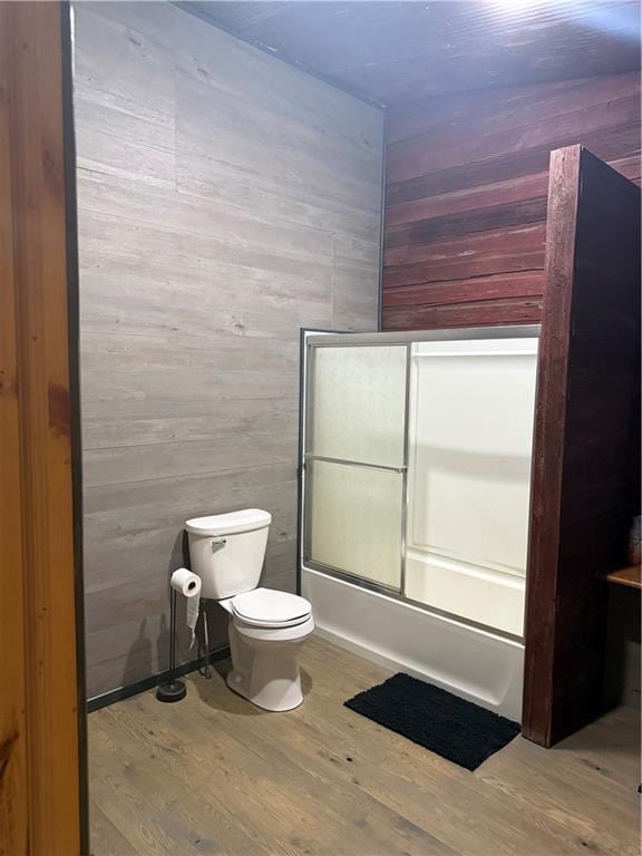 8523 Lakeside Rd, Trego, WI 54888 - bathroom featuring wooden walls, combined bath / shower with glass door, toilet, and wood finished floors