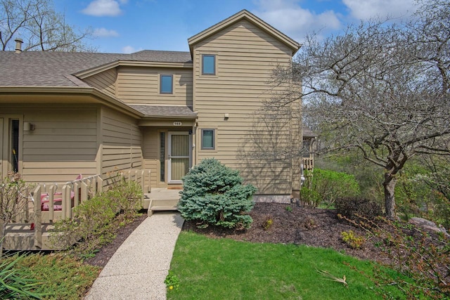 traditional-style house featuring a shingled roof and a front lawn