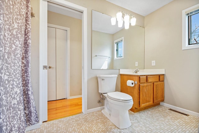 bathroom with a healthy amount of sunlight, baseboards, vanity, and toilet