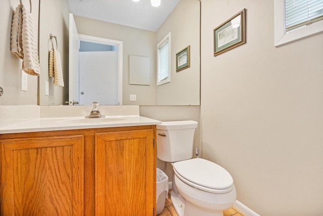 half bathroom featuring toilet, baseboards, tile patterned floors, and vanity