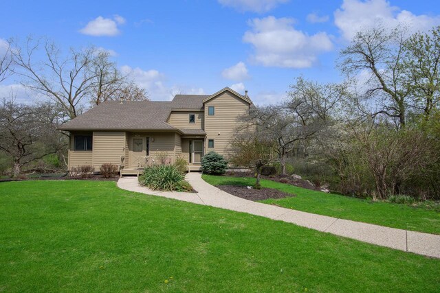 traditional-style home featuring roof with shingles and a front yard
