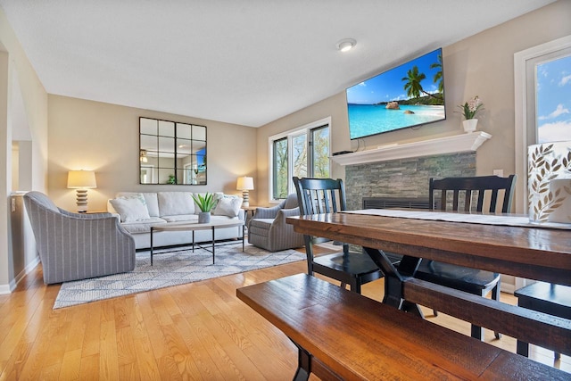 living area featuring light wood-style floors, baseboards, and a fireplace